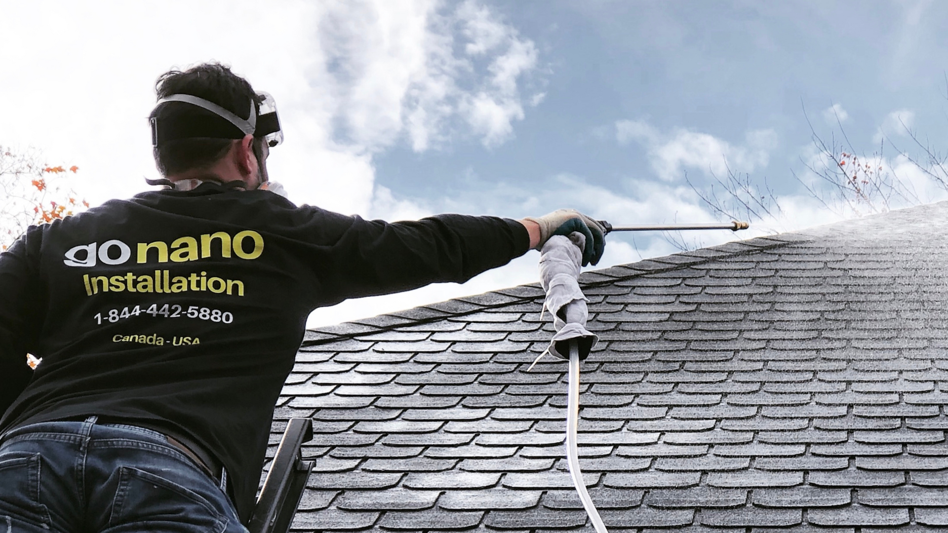 A man is spraying water on a roof with a hose.
