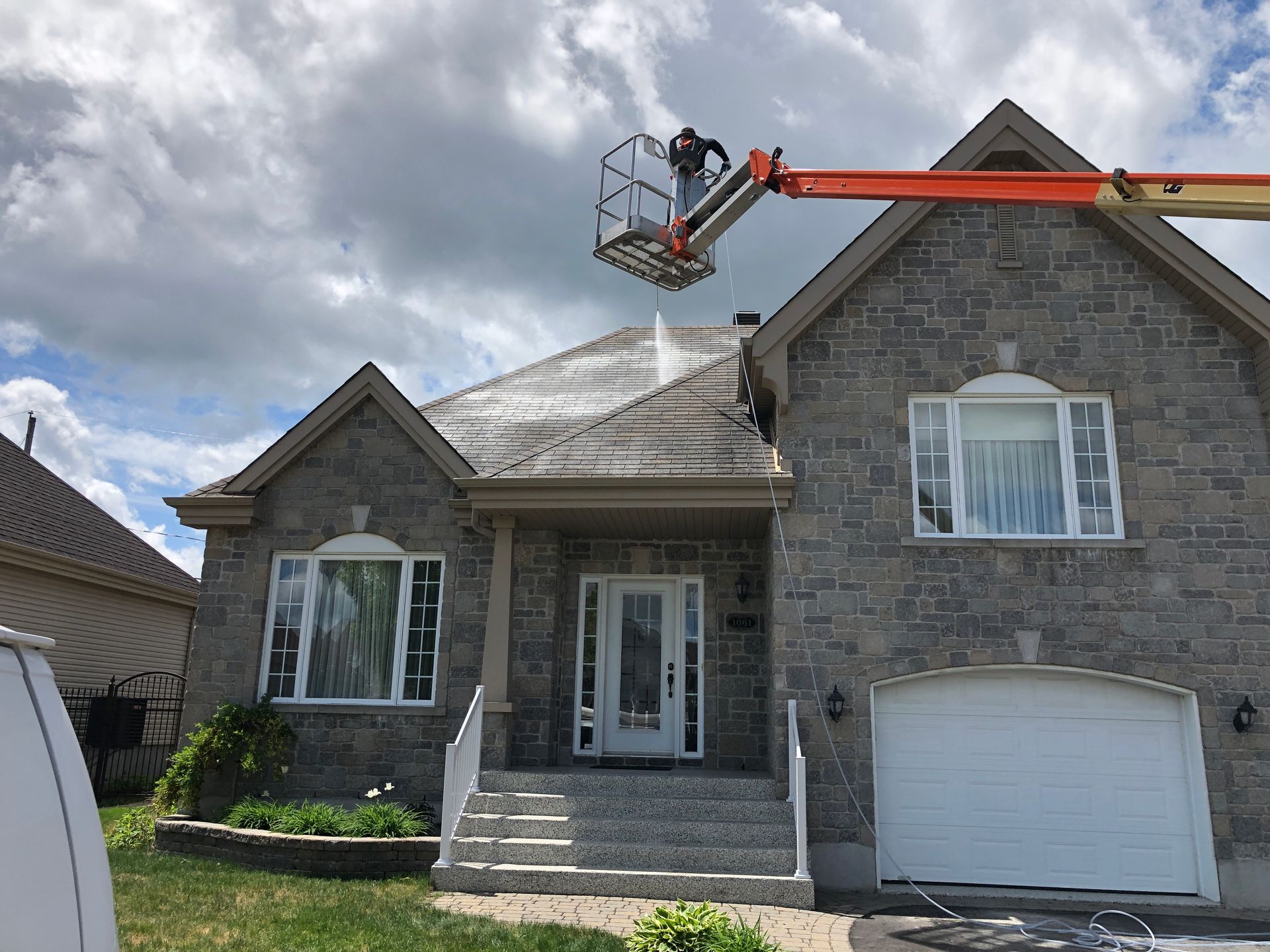 A man is cleaning the roof of a house with a crane.
