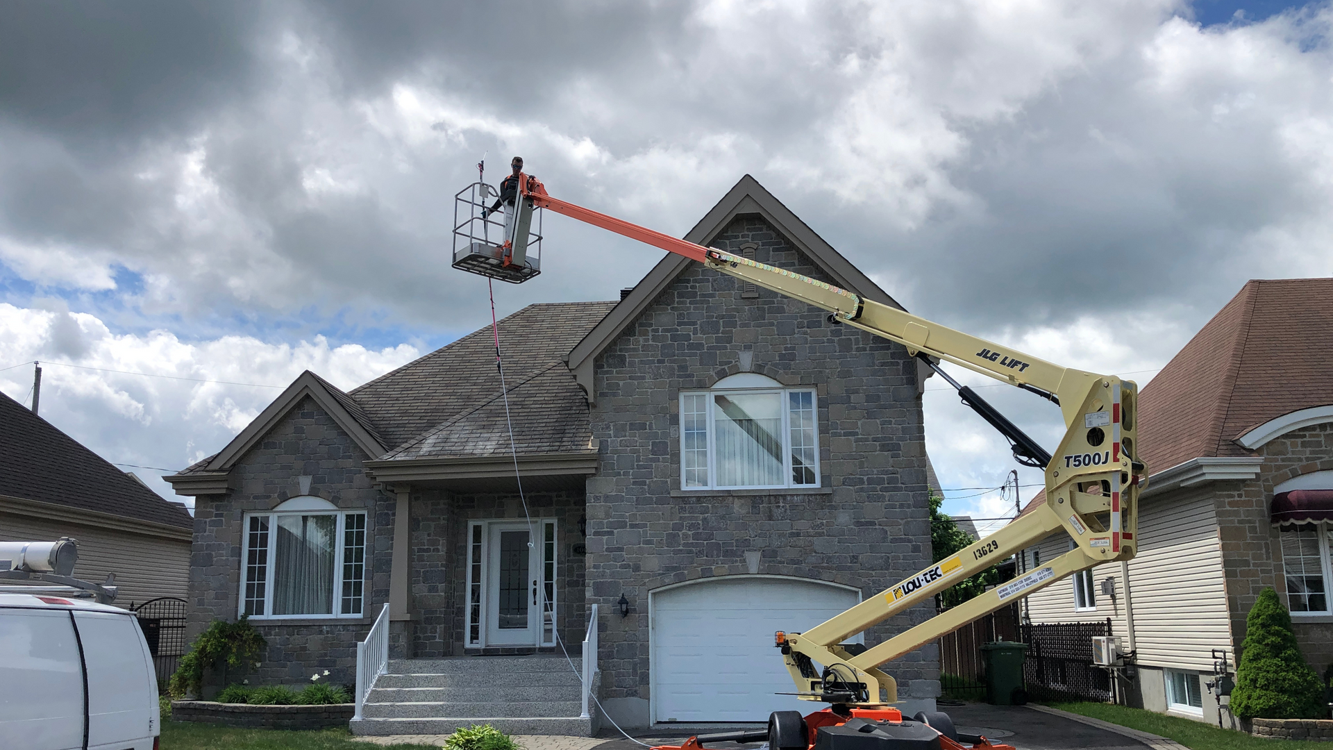 A man is working on the roof of a house with a crane.