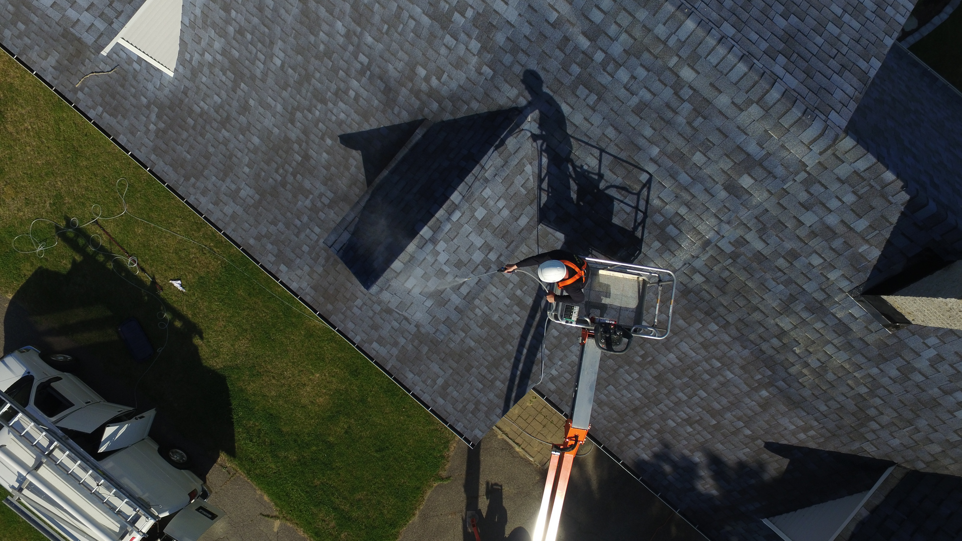 An aerial view of a man working on a roof with a crane.