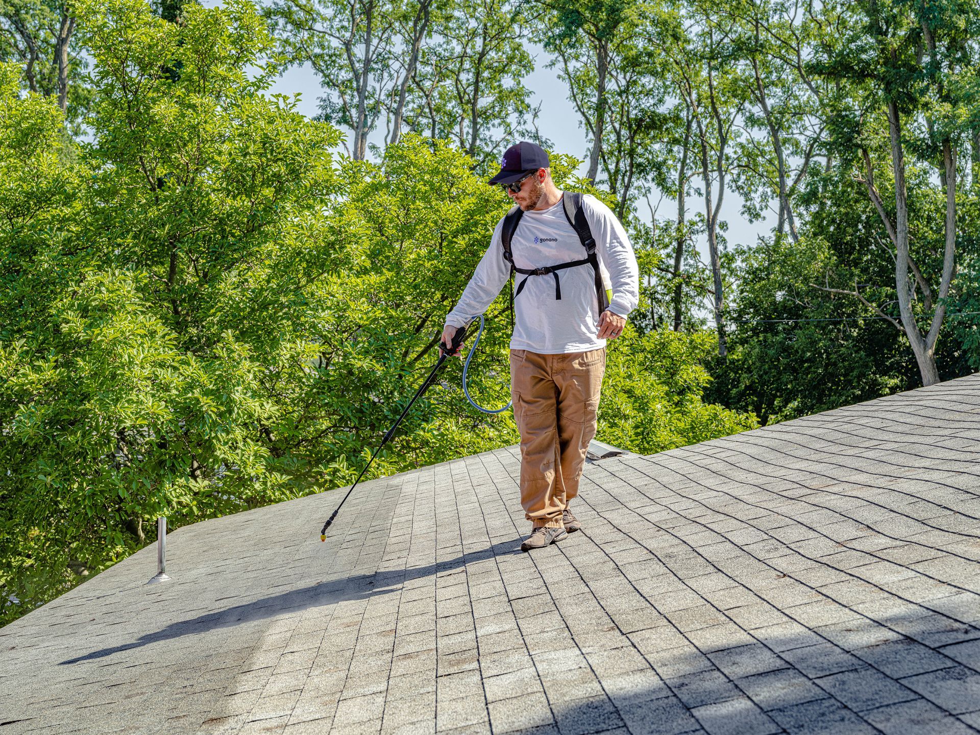 A man is spraying a roof with a sprayer.