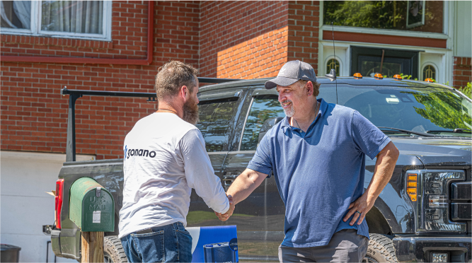 Two men are shaking hands in front of a truck.