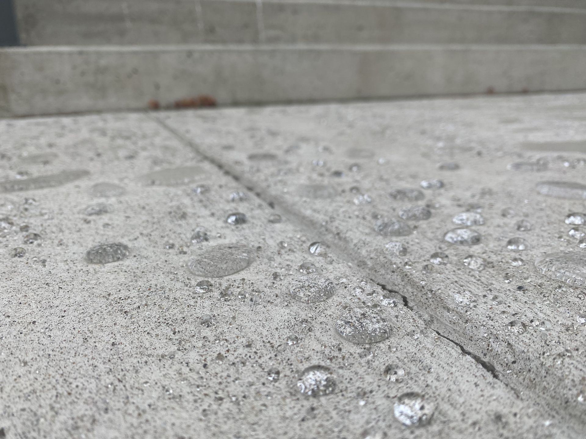 A close-up of a concrete floor with water drops on it.