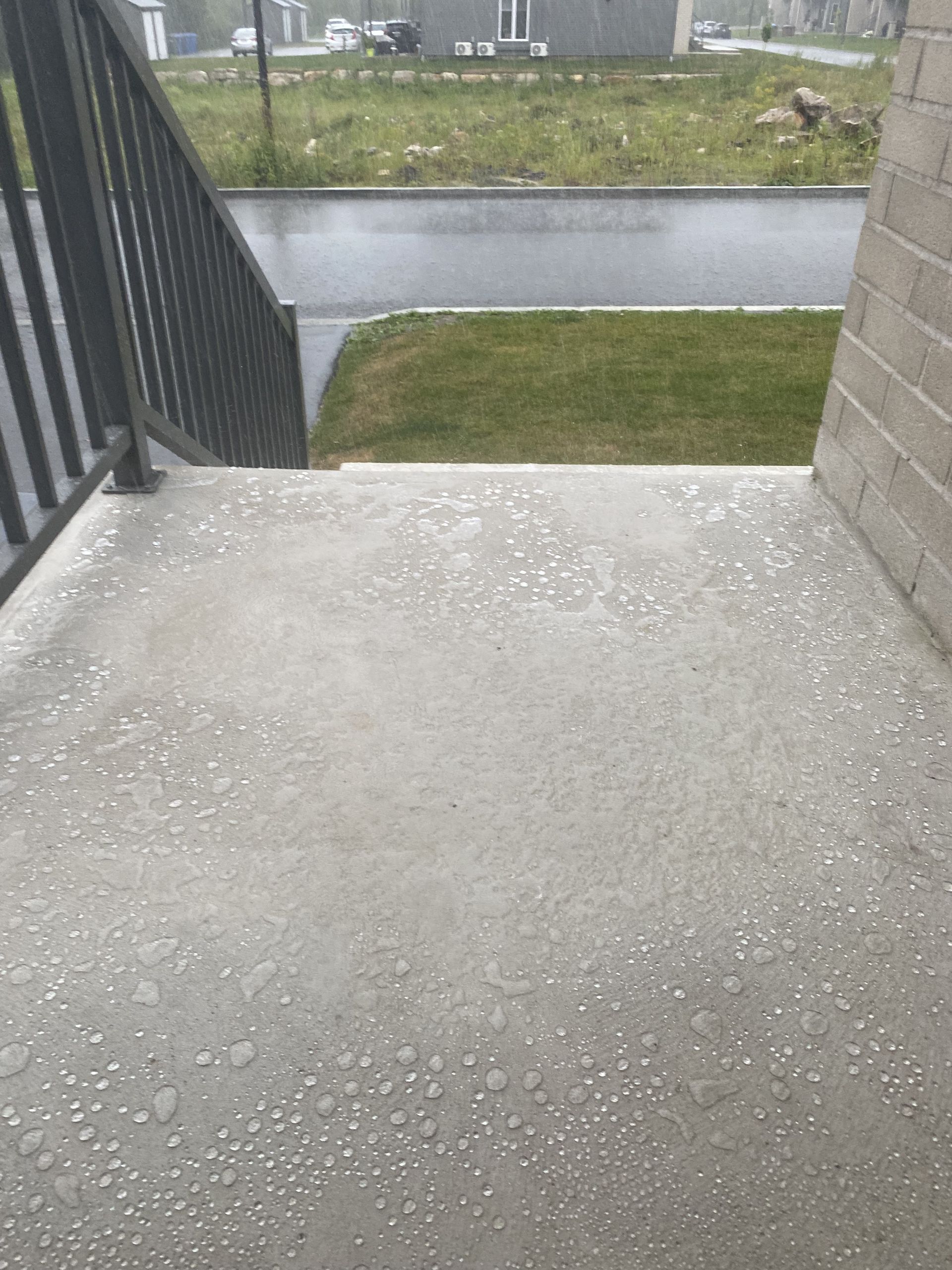 A balcony with stairs leading up to a grassy area and a brick building.