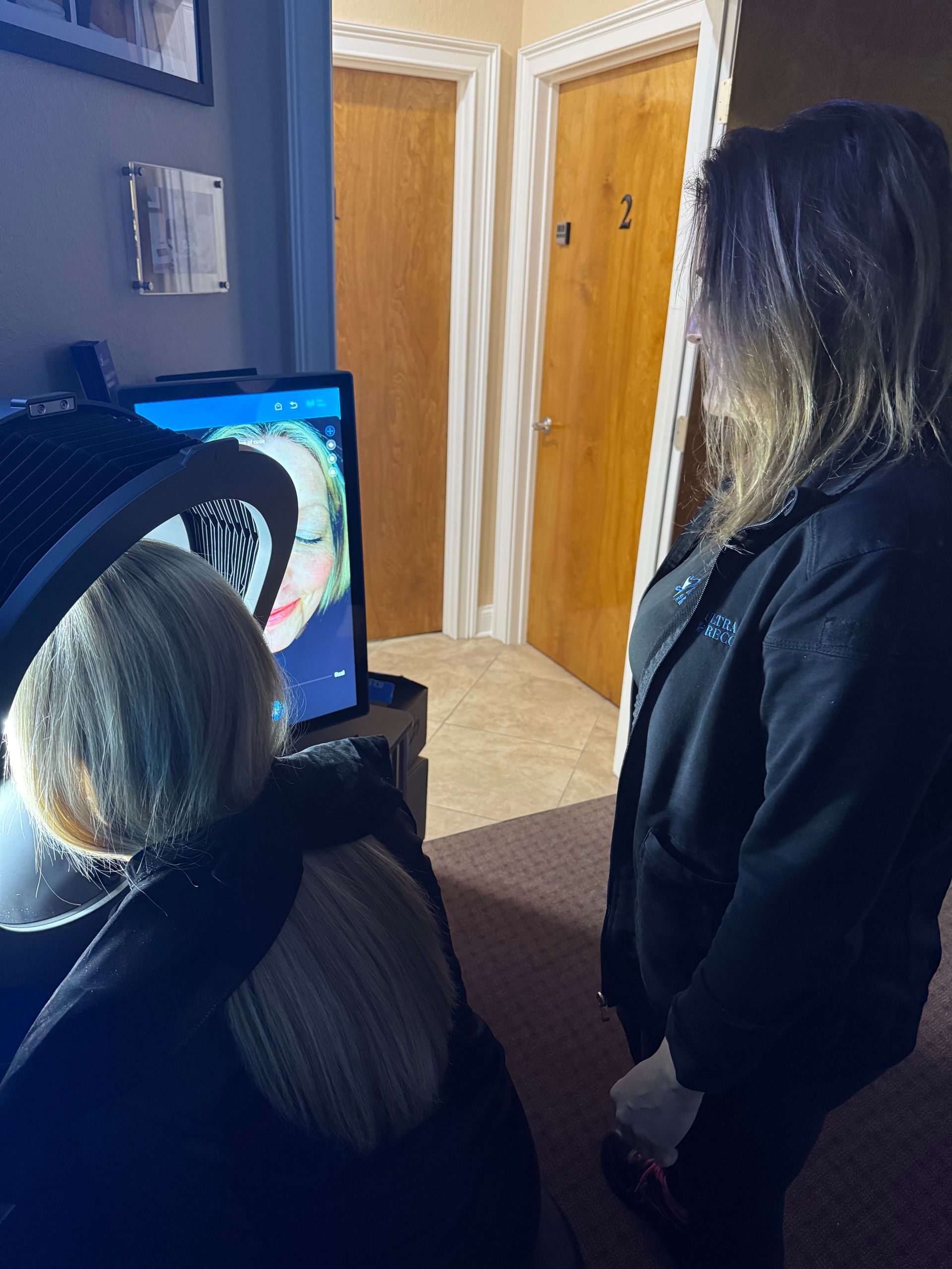 Two people looking at a computer screen in a hallway with wooden doors