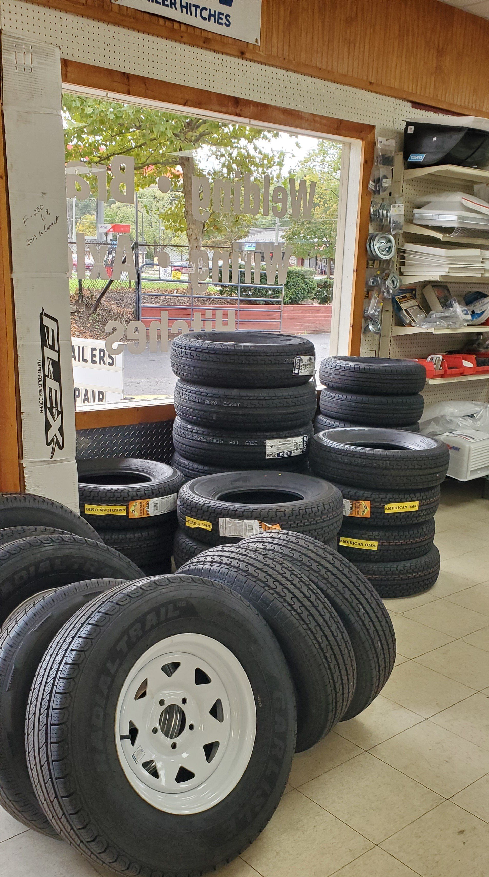 A bunch of tires and wheels are stacked on top of each other in a store.