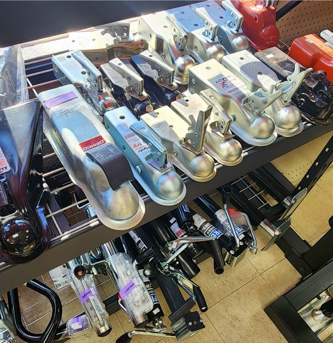 A bunch of trailer couplers are lined up on a shelf