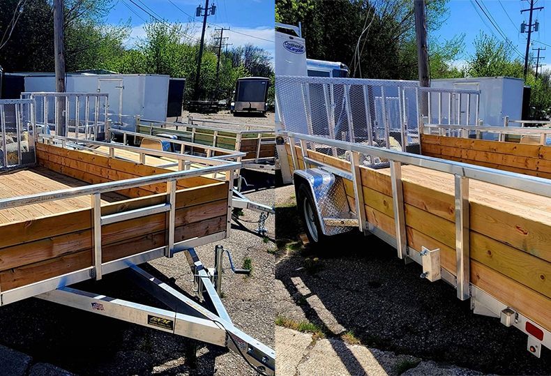 A trailer with a wooden ramp is parked in a parking lot