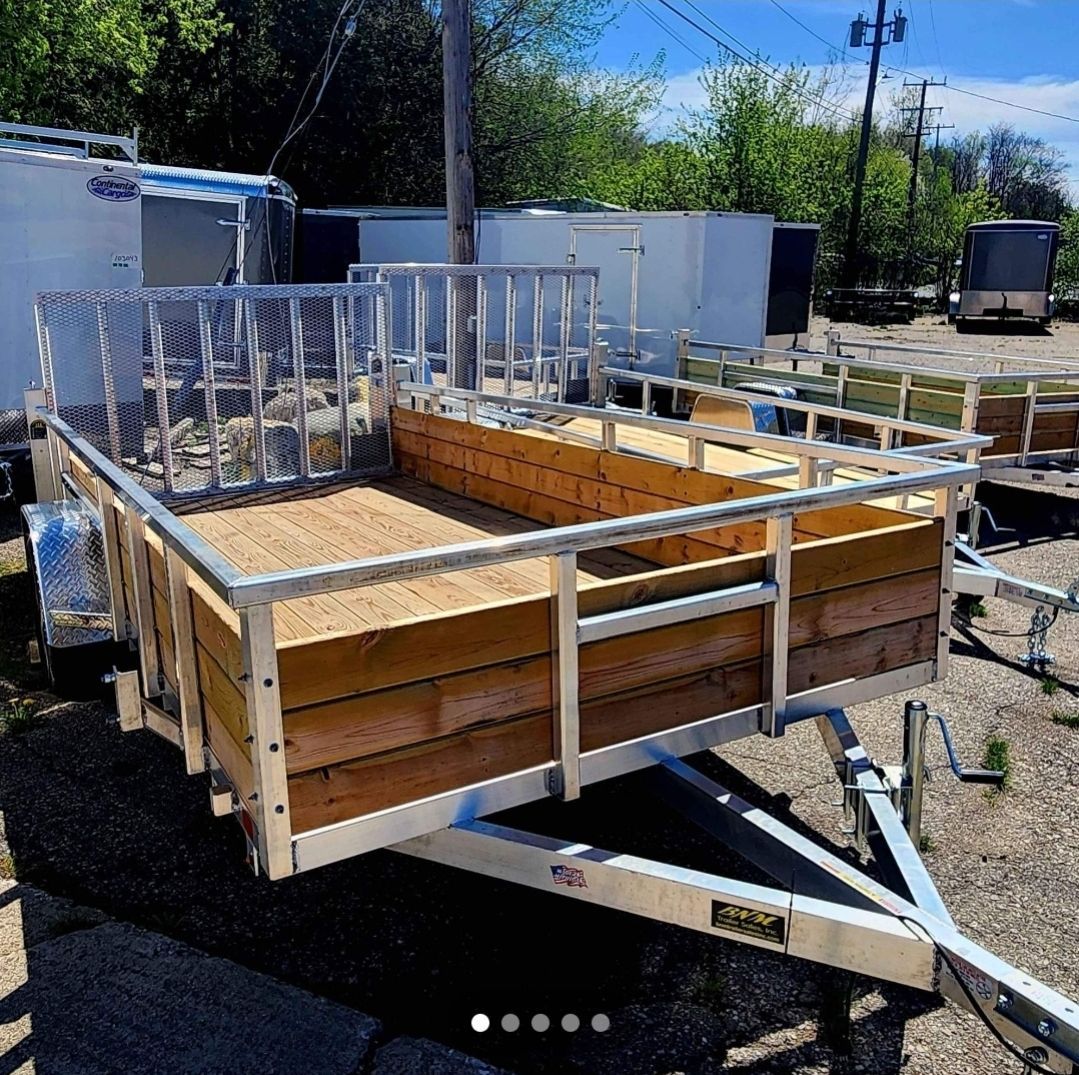 A wooden trailer with a metal frame is parked in a parking lot