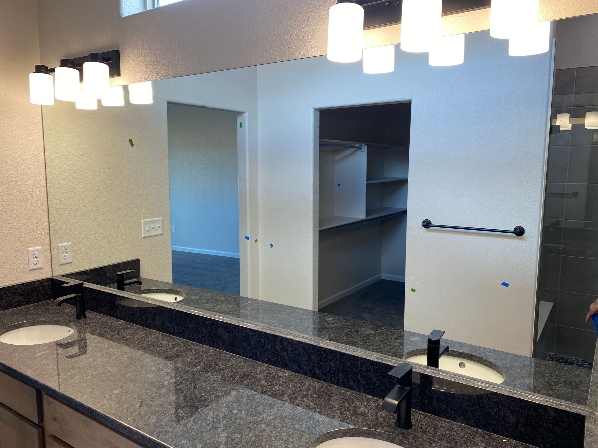 Bathroom with double vanity, large mirror, and overhead lights. 
