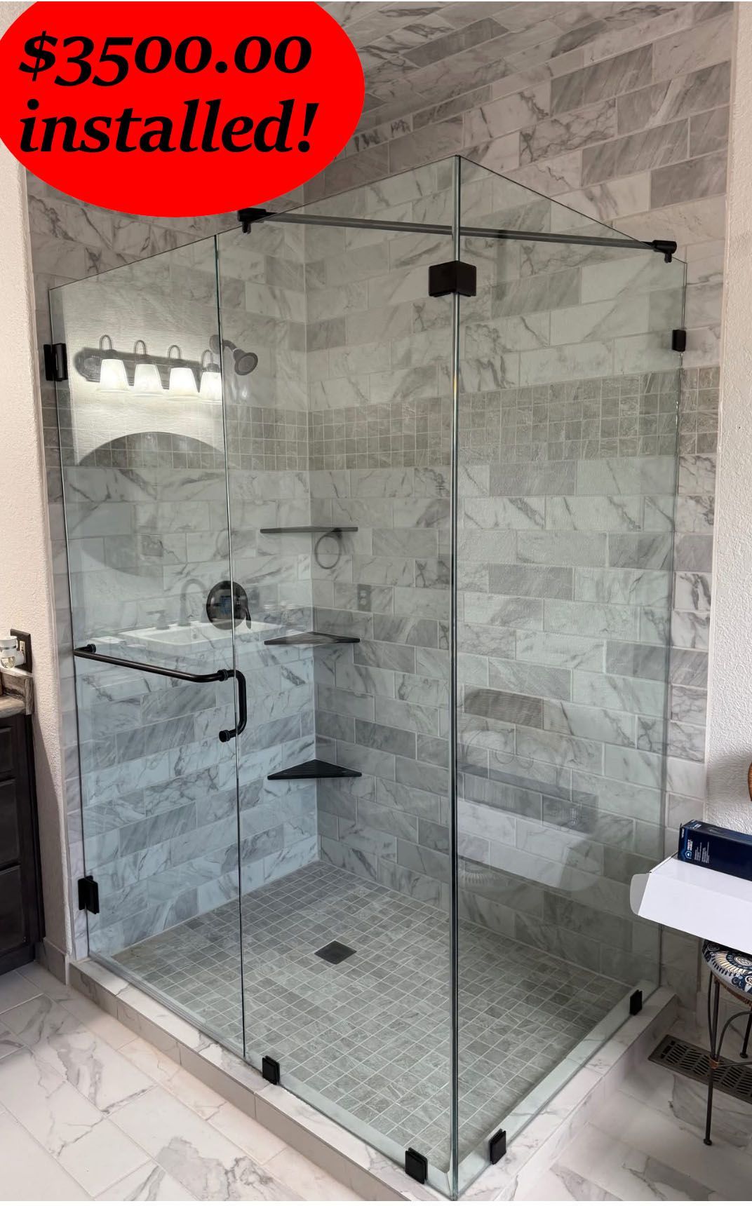 Glass shower enclosure with black hardware and marble tile