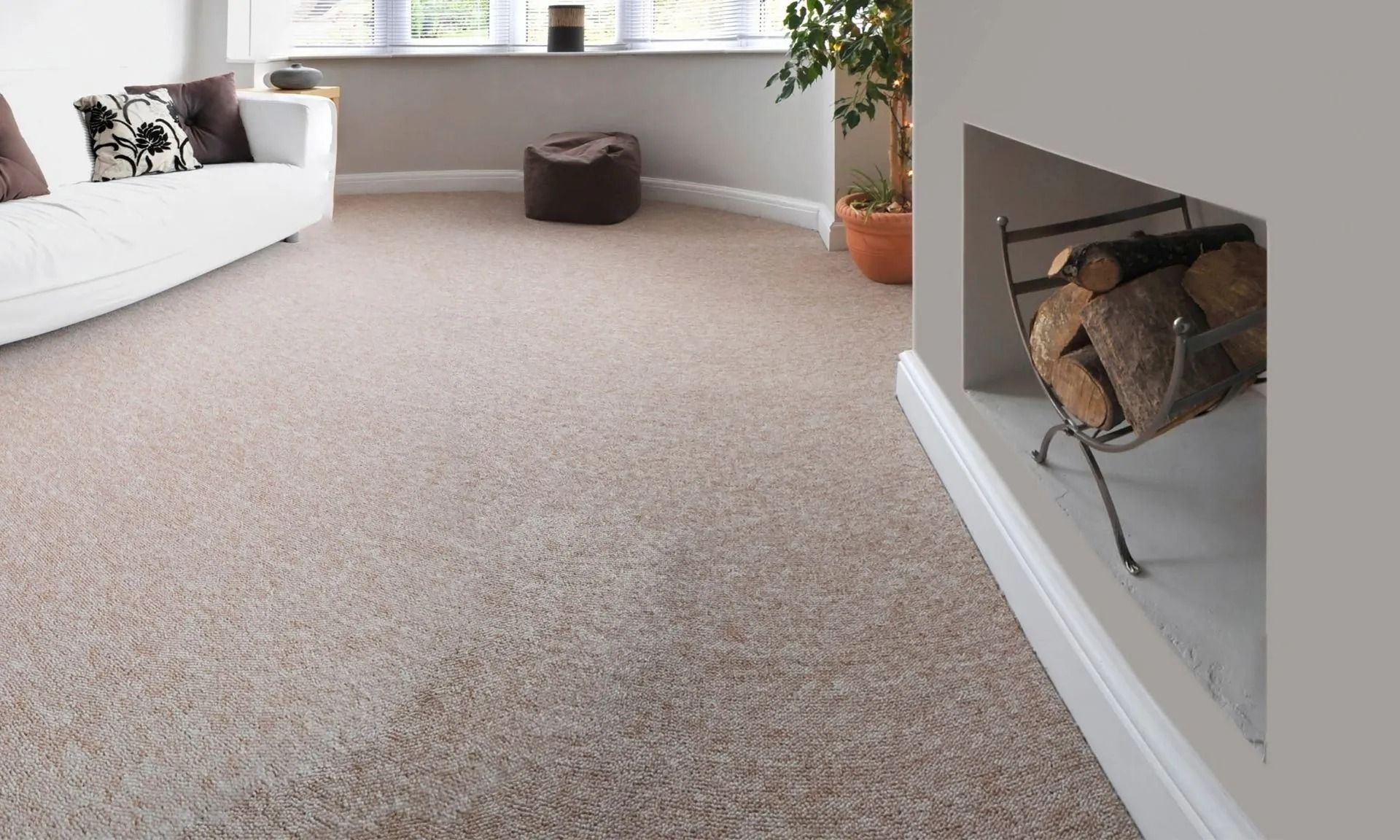 Beige carpet in a living room, with white couch, window, fireplace with logs, and a potted plant.