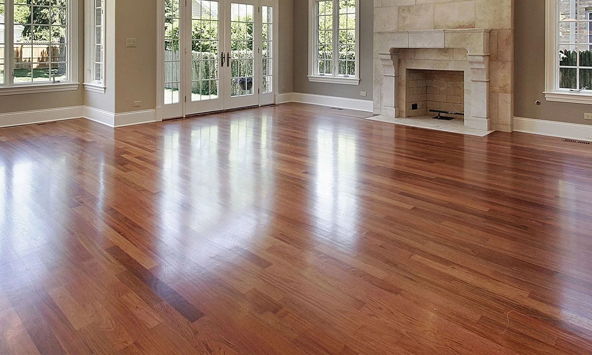 Shiny hardwood floor in a sunlit room with a fireplace and windows.
