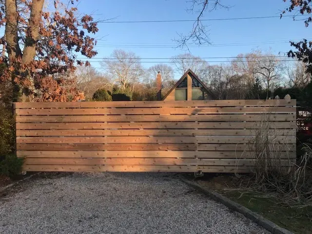 A wooden fence is sitting on top of a gravel driveway.