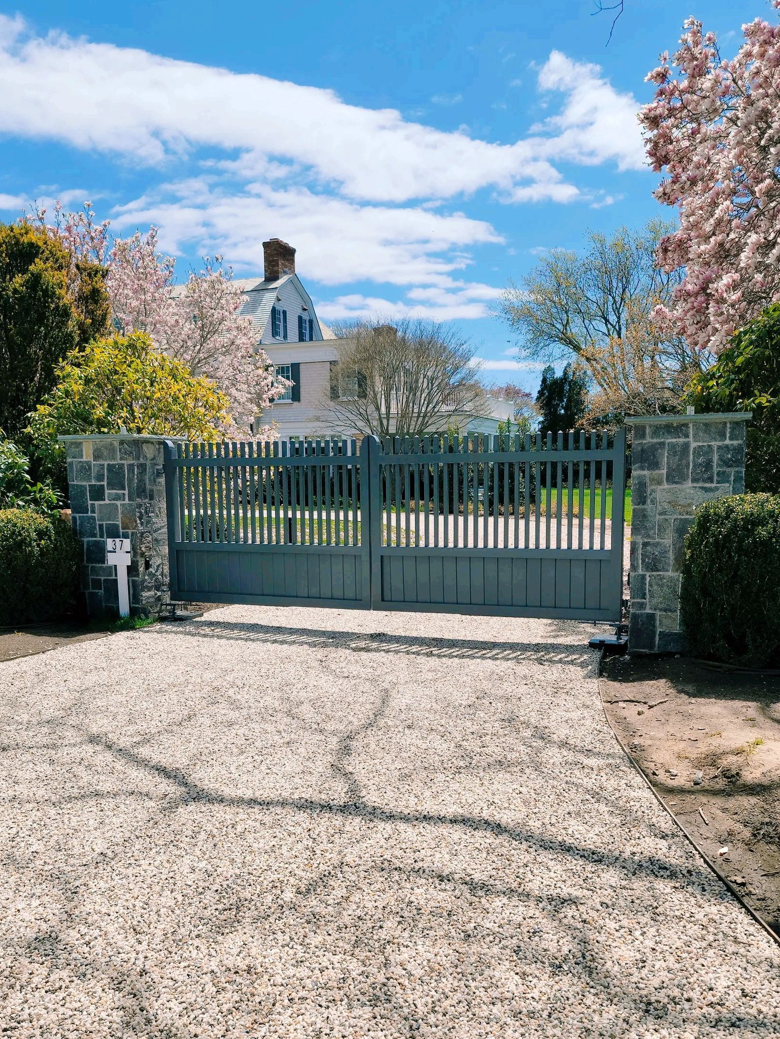 A gravel driveway with a gate leading to a house.