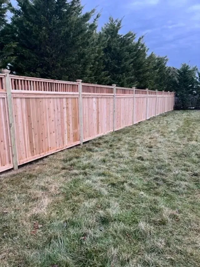 A wooden fence is sitting in the middle of a lush green field.