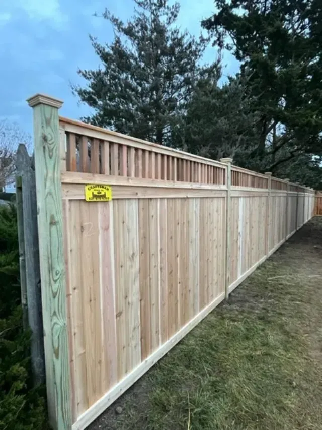 A wooden fence is sitting on top of a dirt road next to trees.