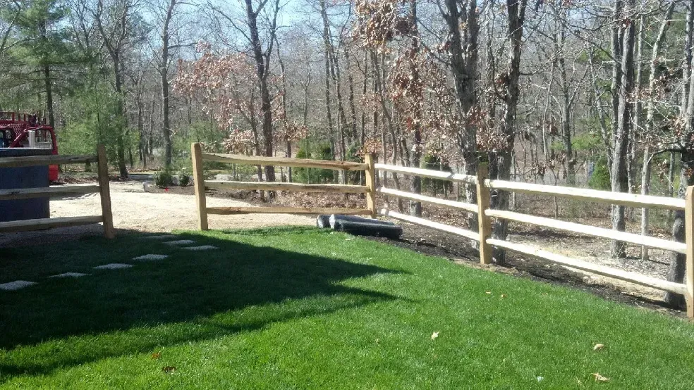 A wooden fence surrounds a lush green yard.