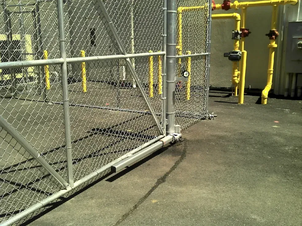 A chain link fence with yellow pipes behind it
