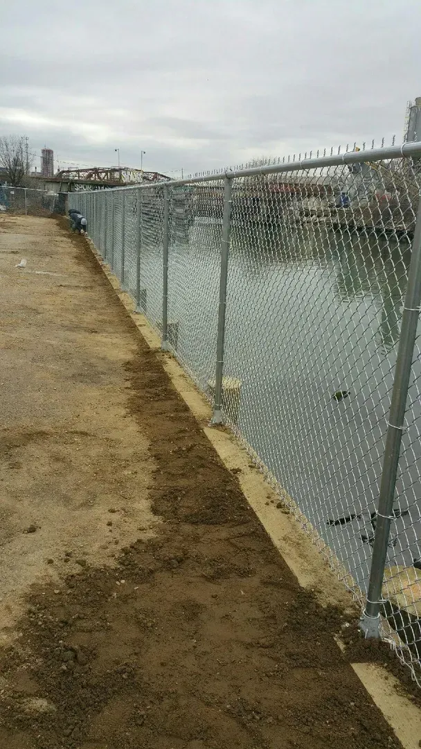 A chain link fence surrounds a body of water.