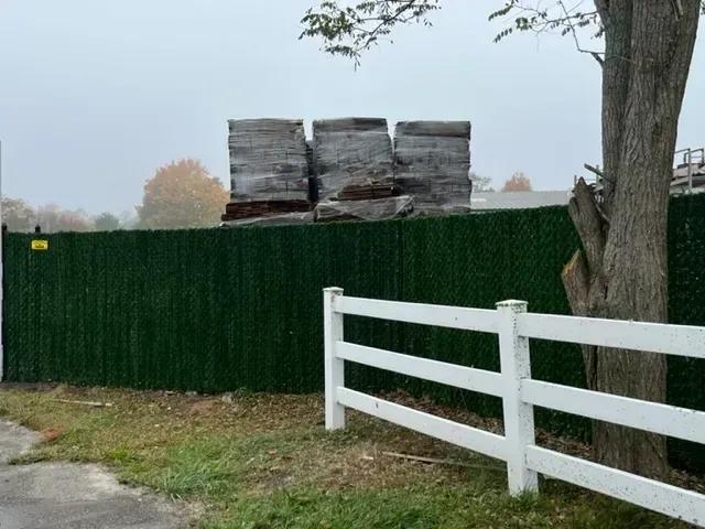 A white fence with a green fence behind it