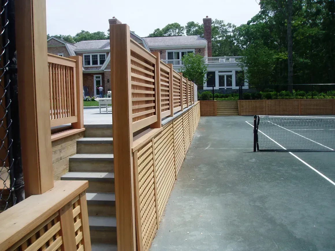 A tennis court with a wooden fence and stairs