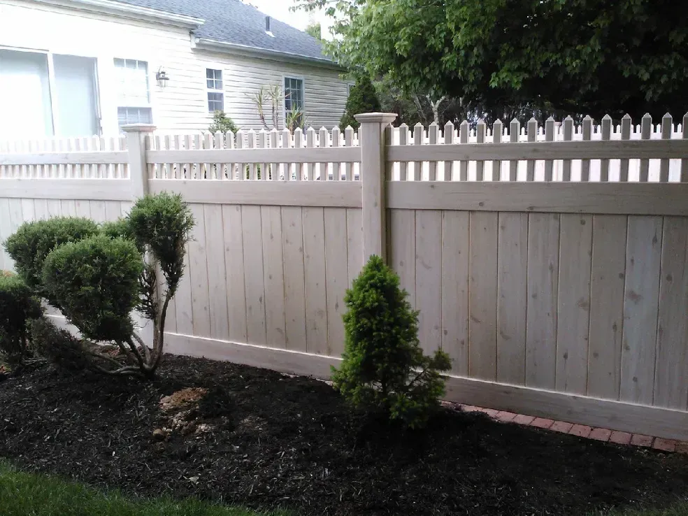 A white wooden fence with a house in the background