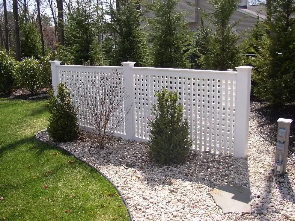 A white lattice fence surrounds a lush green yard