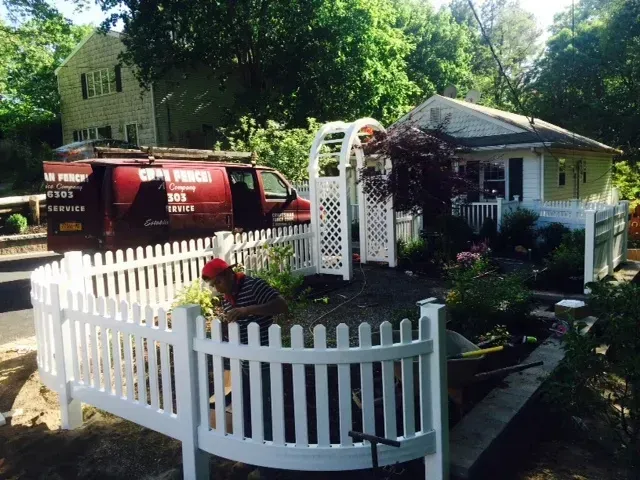 A white picket fence is in front of a house