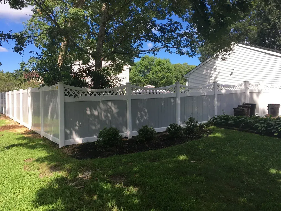 A white fence is in the backyard of a house.