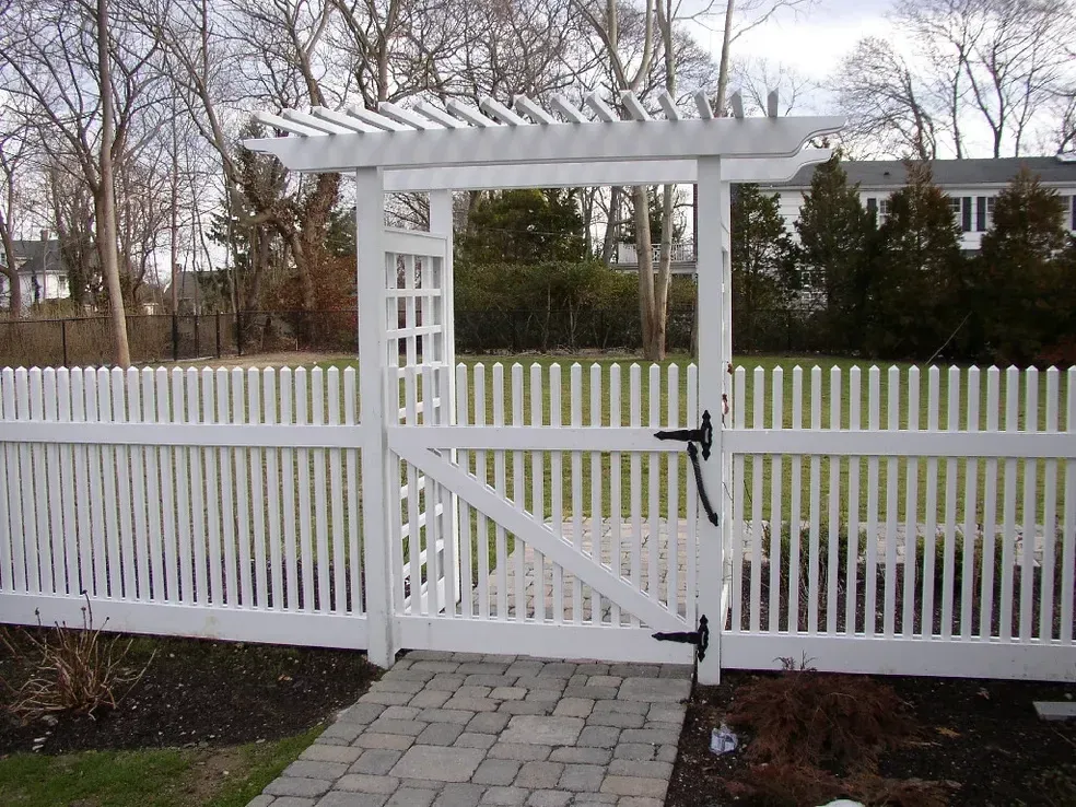A white picket fence with a gate and a pergola