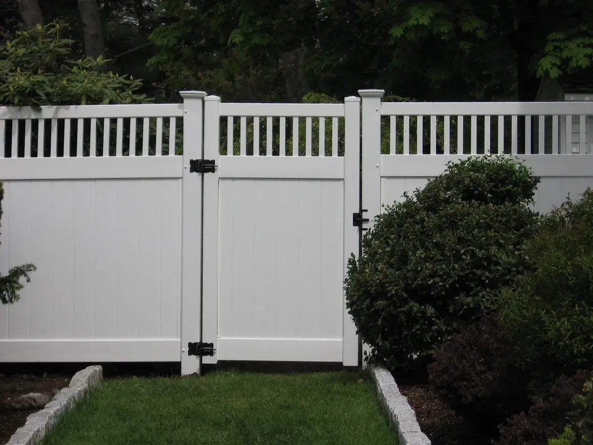 A white fence with a gate in the backyard