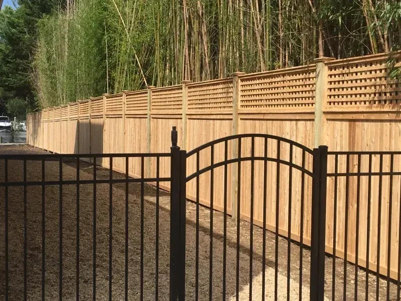 A wooden fence with a metal gate in front of it.