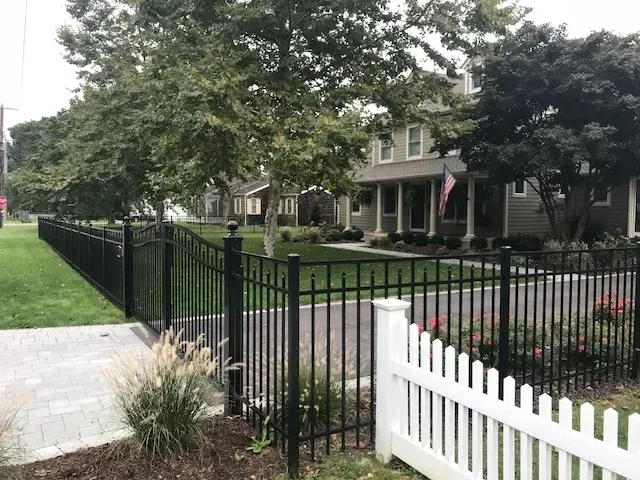 A black fence with a white picket fence in front of a house