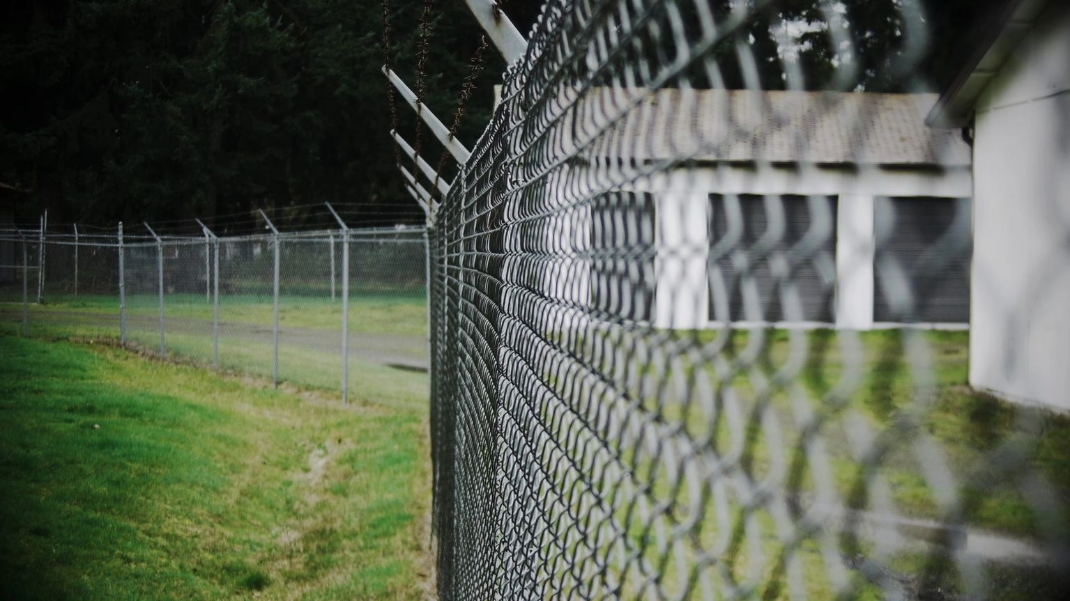 A close up of a chain link fence with barbed wire.