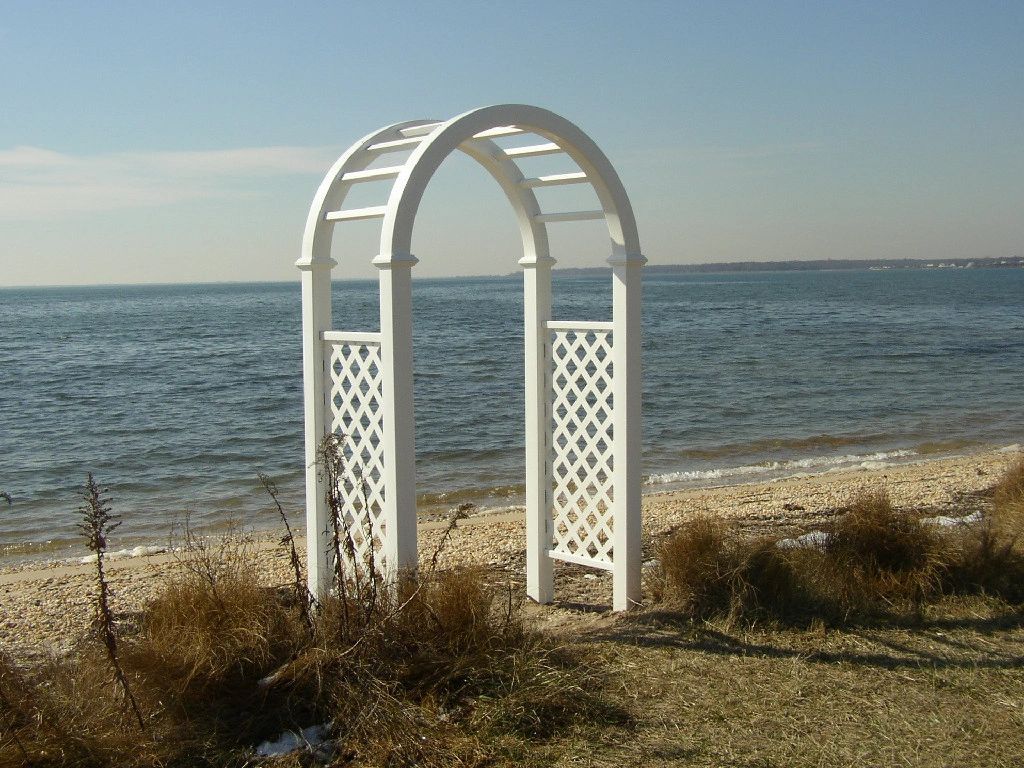 A white archway on a beach overlooking the ocean