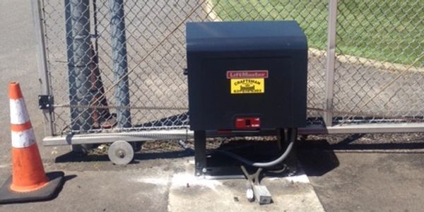 A black box is sitting next to a chain link fence.