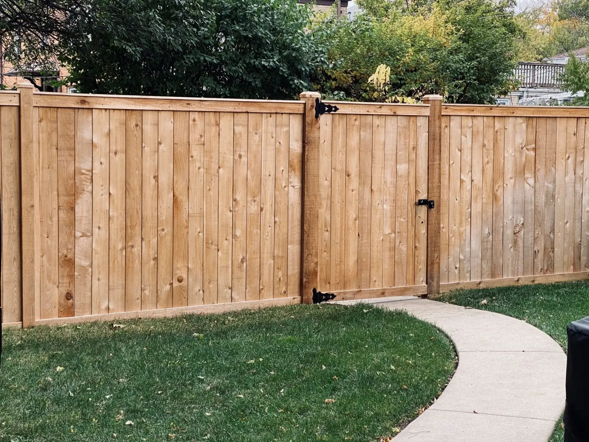 There is a wooden fence with a gate in the backyard.
