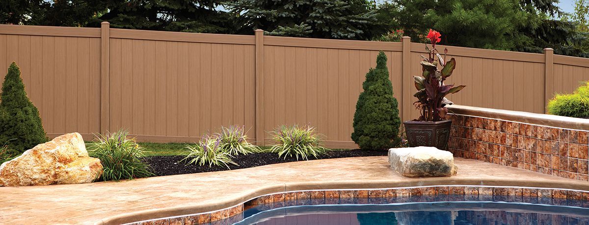 A wooden fence surrounds a swimming pool in a backyard.