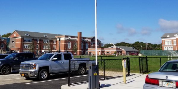 A white truck is parked in a parking lot in front of a brick building.