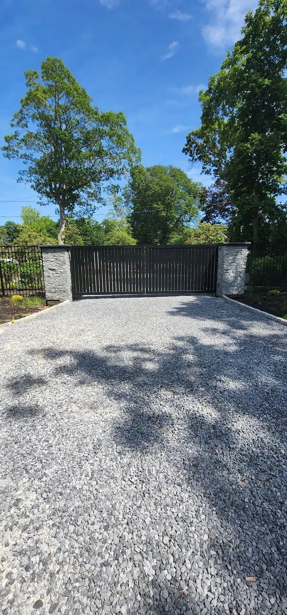 A gravel driveway with a gate and trees in the background
