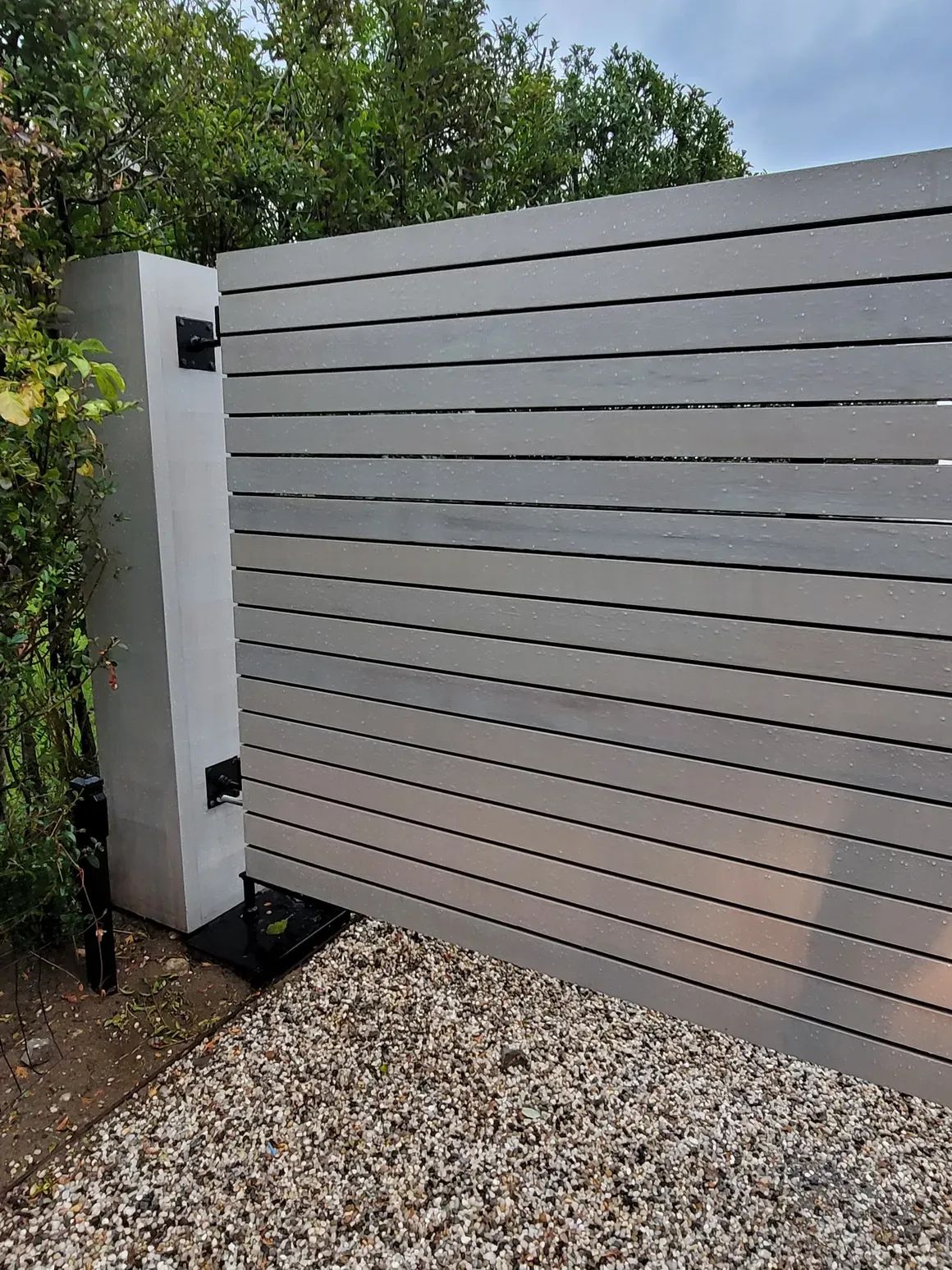 A white fence is sitting on top of a gravel driveway