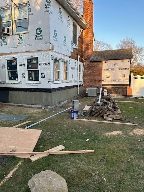 A house is being remodeled with a lot of pieces of wood in front of it.