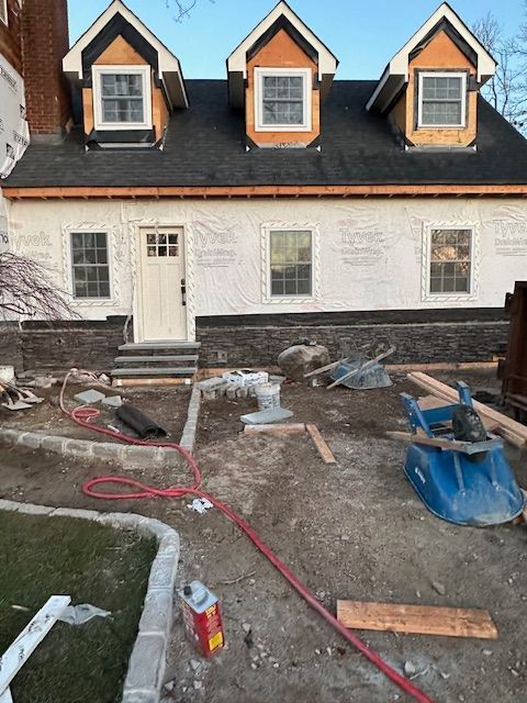 A house that is being remodeled with a hose in front of it.