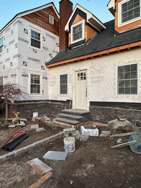A house that is being built with a wheelbarrow in front of it.