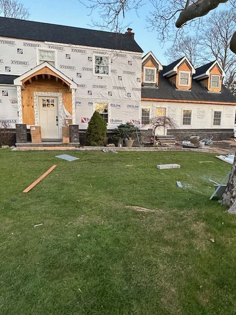 A house that is being remodeled with a large lawn in front of it.