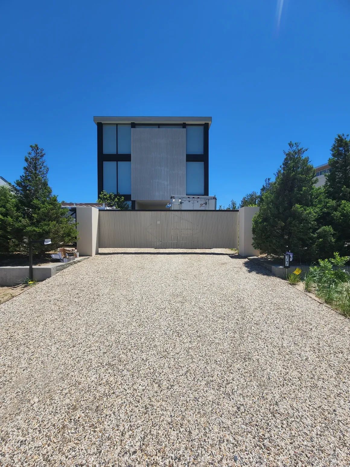 A gravel driveway leads to a large house