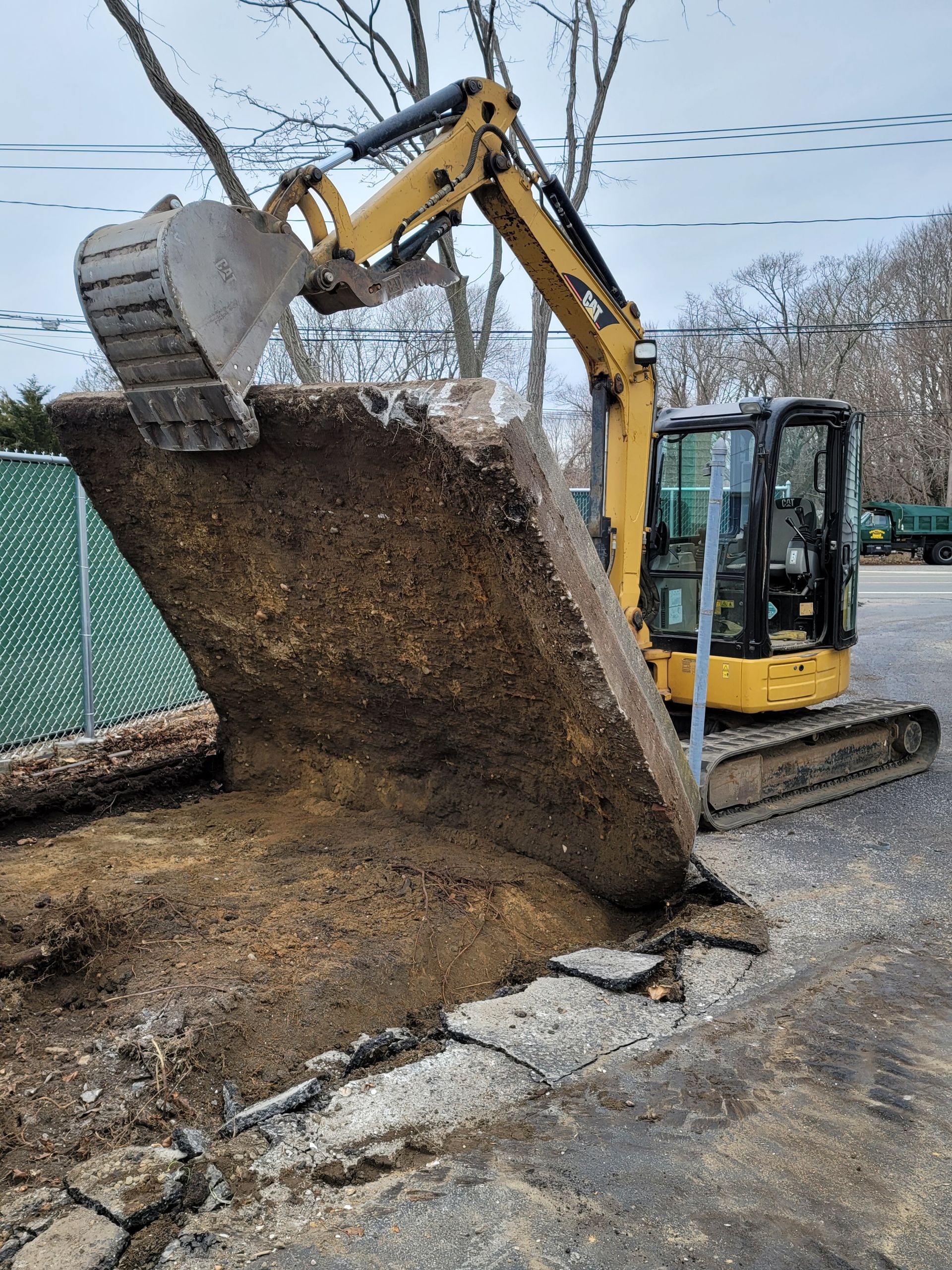 A yellow excavator is digging a hole in the ground.