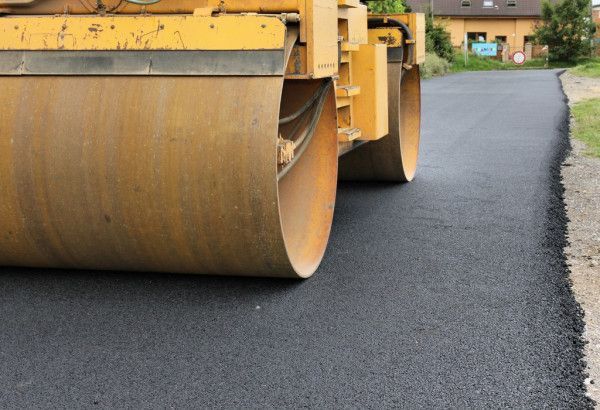 A yellow roller is rolling asphalt on a road.