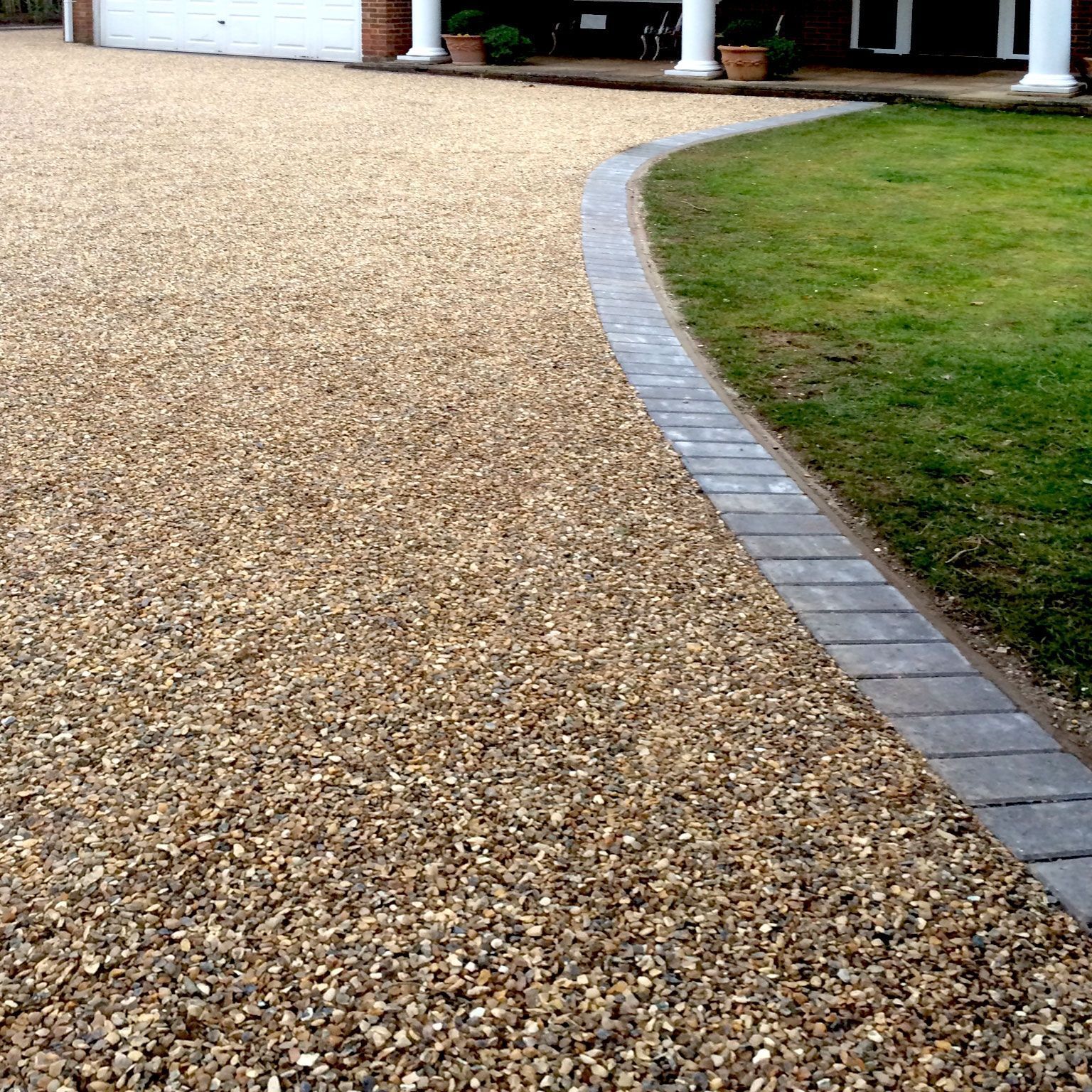 A gravel driveway leading to a house with a brick border.